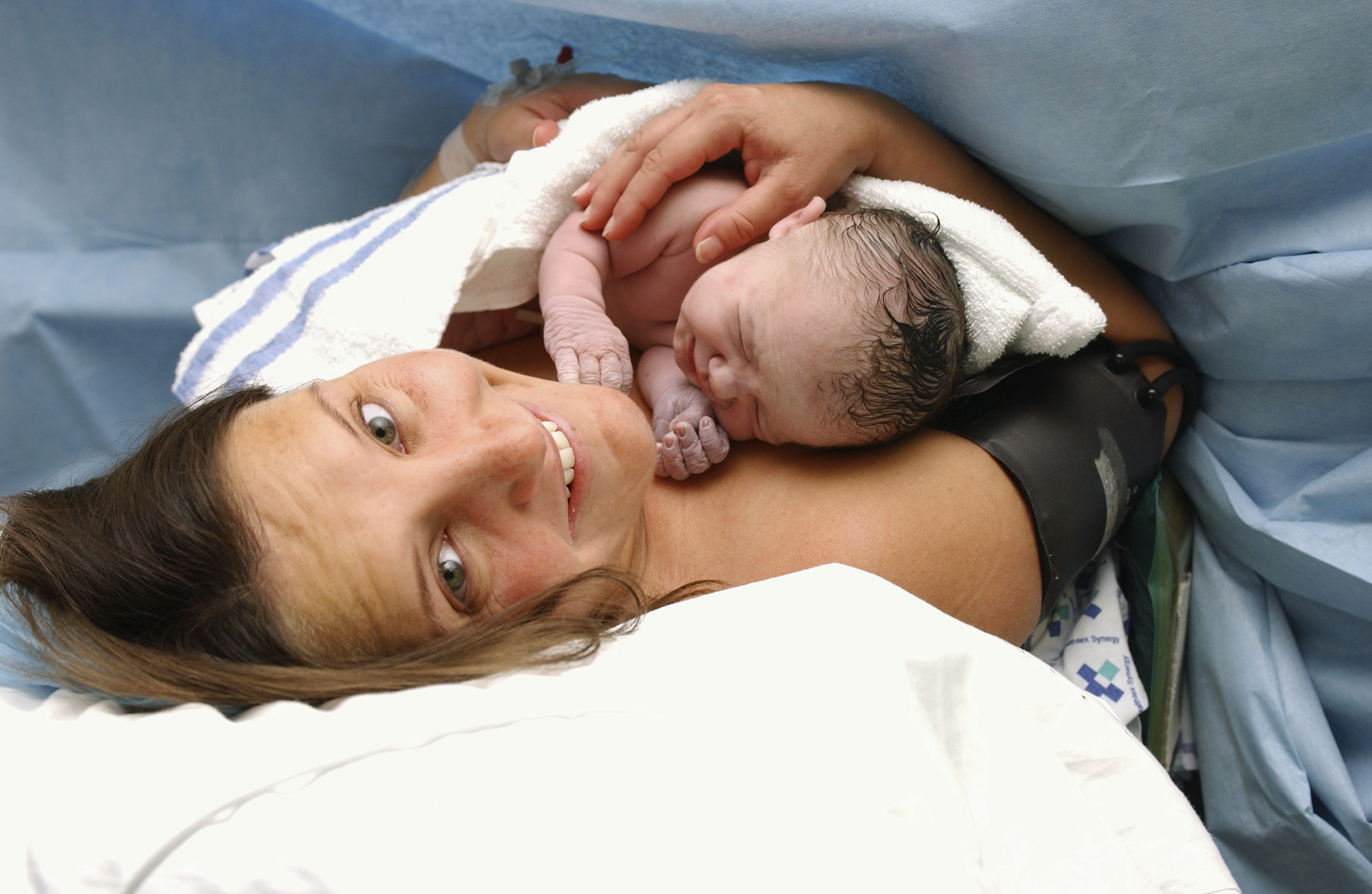 Женщина рожает дочку. Естественное рождение ребенка.