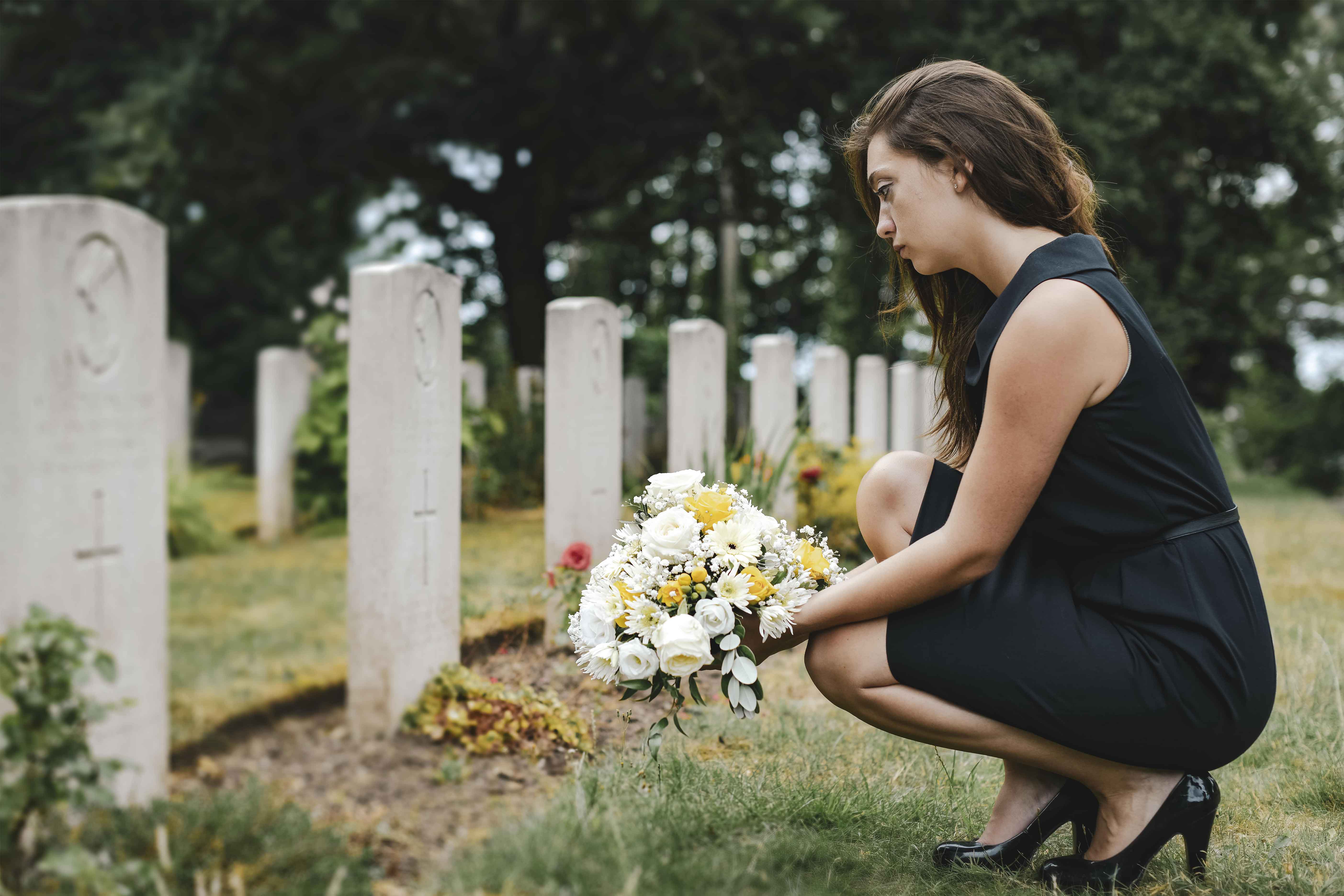 Женщина похоронившая мужей. Цветы на могилу. Женщина у могилы.